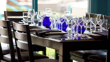Una mesa de comedor dispuesta con sillas, vasos y un florero azul.