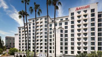 A Marriott hotel with a symmetrical facade, multiple balconies, and palm trees in front.