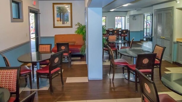 Uma sala de jantar com mesas, cadeiras, um sofá e um quadro na parede.