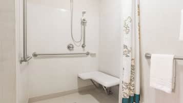 A bathroom with a shower, grab bar, bench, and a towel rack.