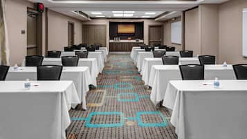 Un salón de conferencias con filas de mesas, sillas y un atril.