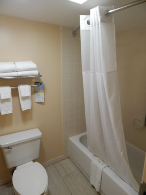 Bathroom features a bathtub, shower, and toilet, with a towel rack and towels.