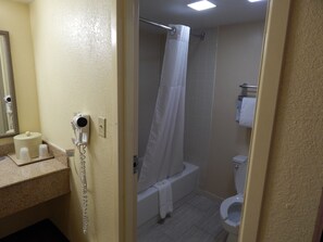 Bathroom features a shower, toilet, and countertop with amenities.