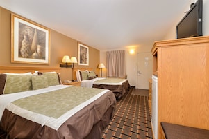 A hotel room with two beds, a television, a desk, and a bathroom.