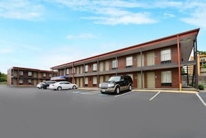 A motel with multiple floors, a parking lot, and several cars parked in front.