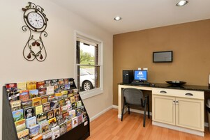 A room with a desk, a computer, a chair, a bookshelf, a clock, and a window.