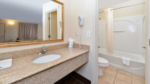 A bathroom with a granite countertop sink, a mirror, a hairdryer, and a bathtub. - Americas Best Value Inn Nashville Downtown (Nashville)