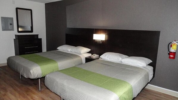 A hotel room with two beds, a nightstand, a mirror, a wall-mounted light, and a fire extinguisher.