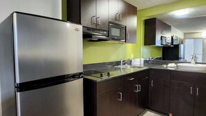 Una cocina con electrodomésticos de acero inoxidable, gabinetes oscuros y una pared de acento verde.