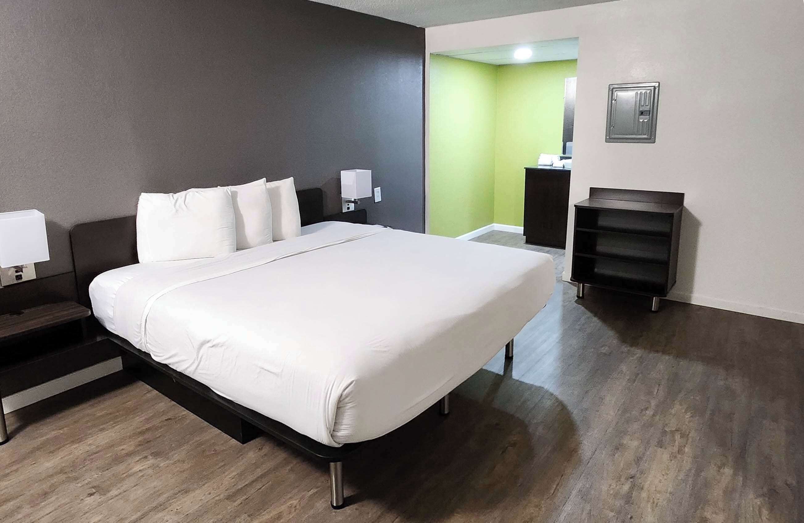Una habitación de hotel moderna con una cama grande, mesitas de noche, un escritorio y un armario.