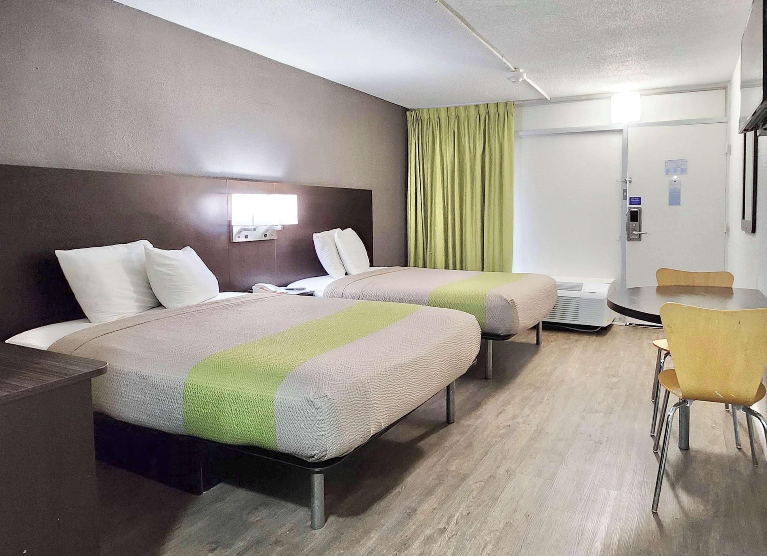 A hotel room with two beds, a desk, and a chair.