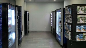 Un pasillo con máquinas expendedoras a ambos lados, incluyendo refrigeradores de Pepsi y una exhibición de la revista Columbus.