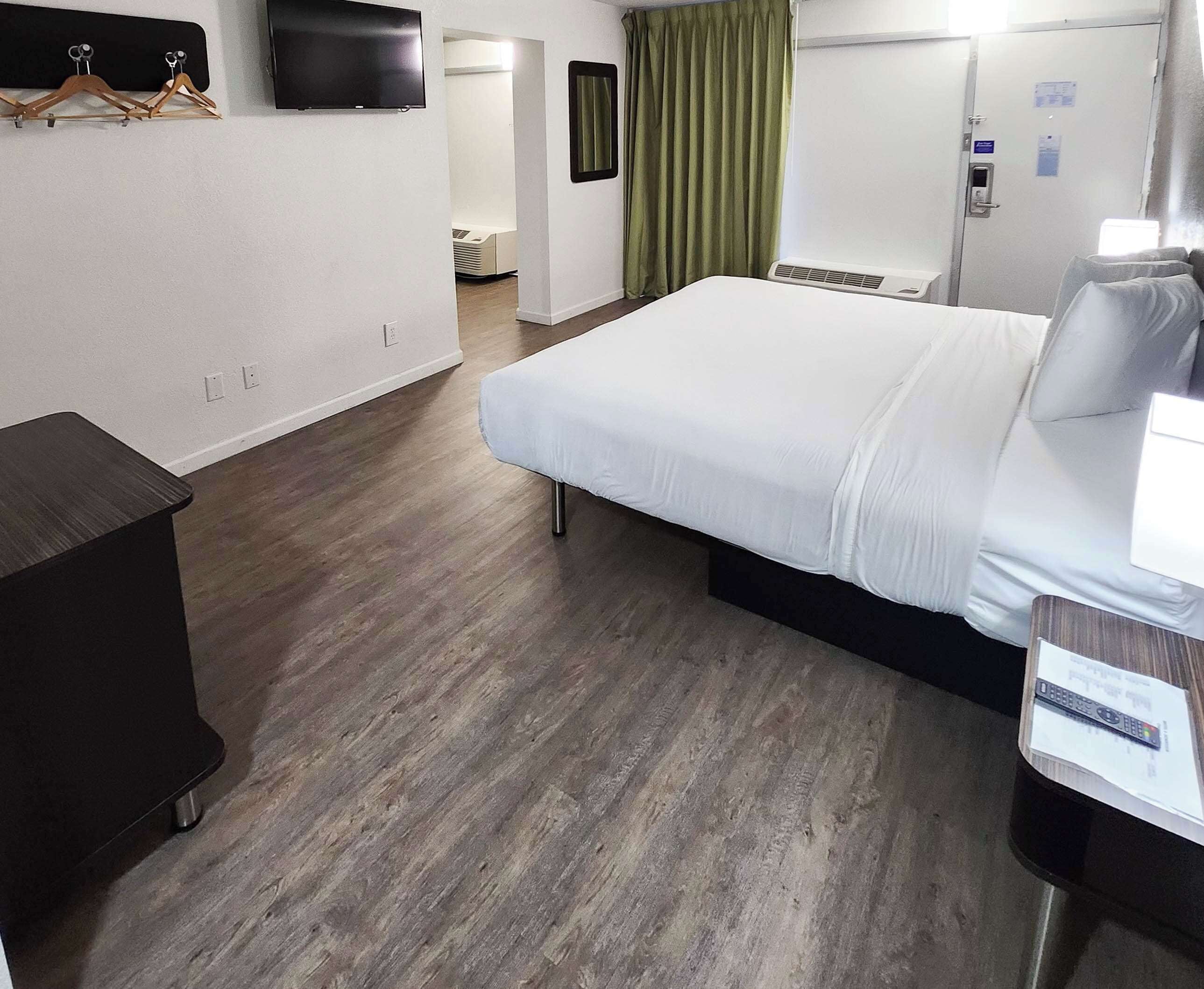 Une chambre d’hôtel avec un lit, un bureau, une télévision et une fenêtre avec des rideaux.