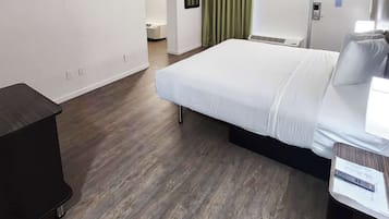 Une chambre d’hôtel avec un lit, un bureau, une télévision et une fenêtre avec des rideaux.