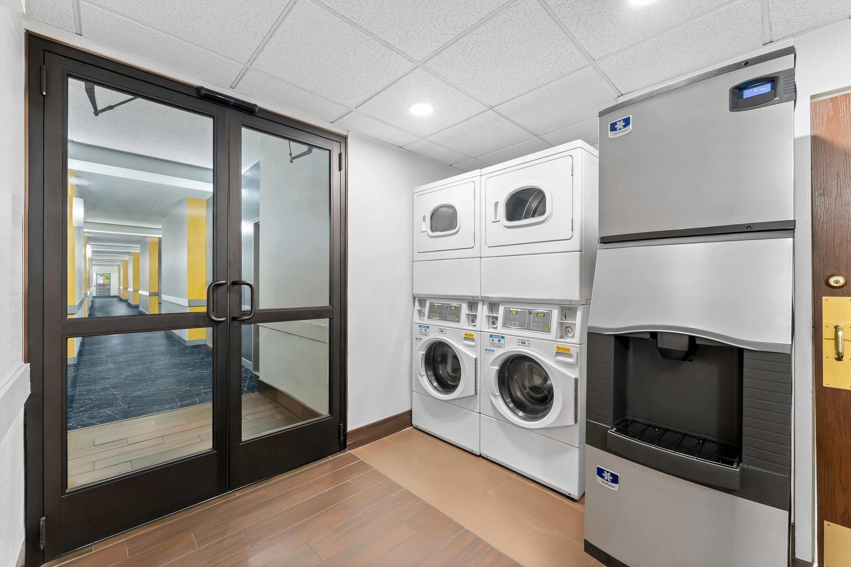 Un espace buanderie équipé d’un lave-linge, d’un sèche-linge et d’un distributeur d’eau.