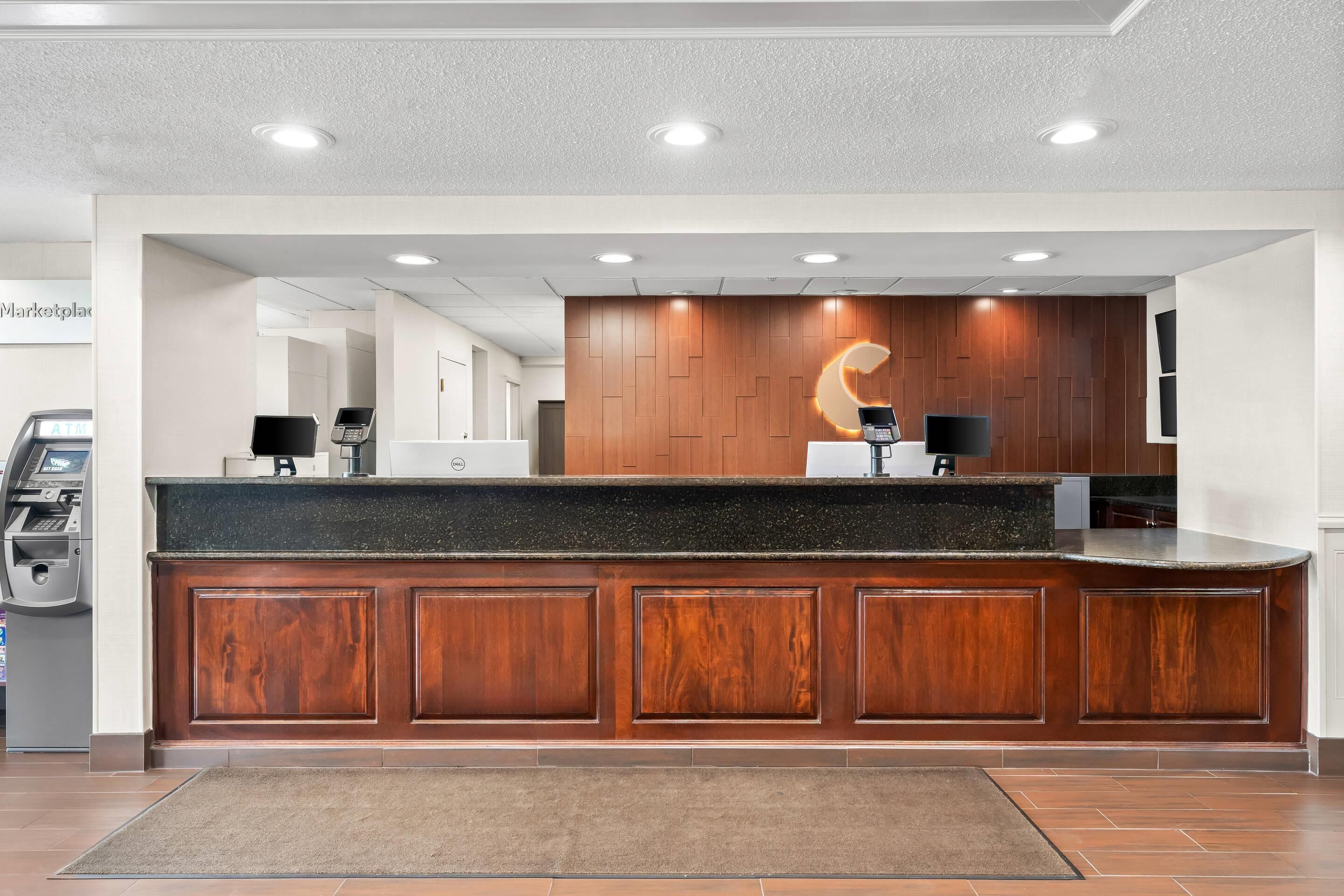 Una zona de recepción con mostrador de madera, caja registradora y quiosco digital.