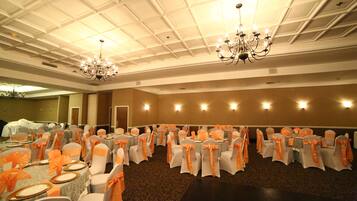Une salle de banquet avec des tables rondes et des chaises, des lustres et des appliques murales.