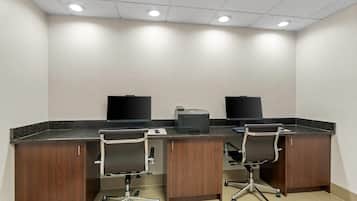 A conference room with two desks, chairs, a printer, and a black screen on each desk.