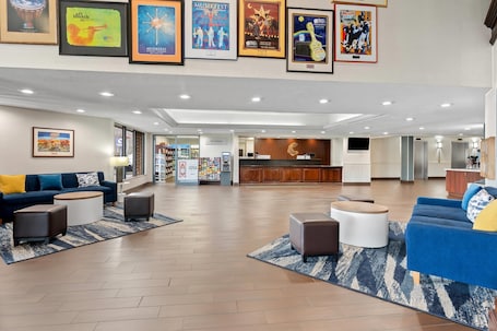A spacious lobby with a reception desk, seating areas, and a variety of framed posters on the walls.