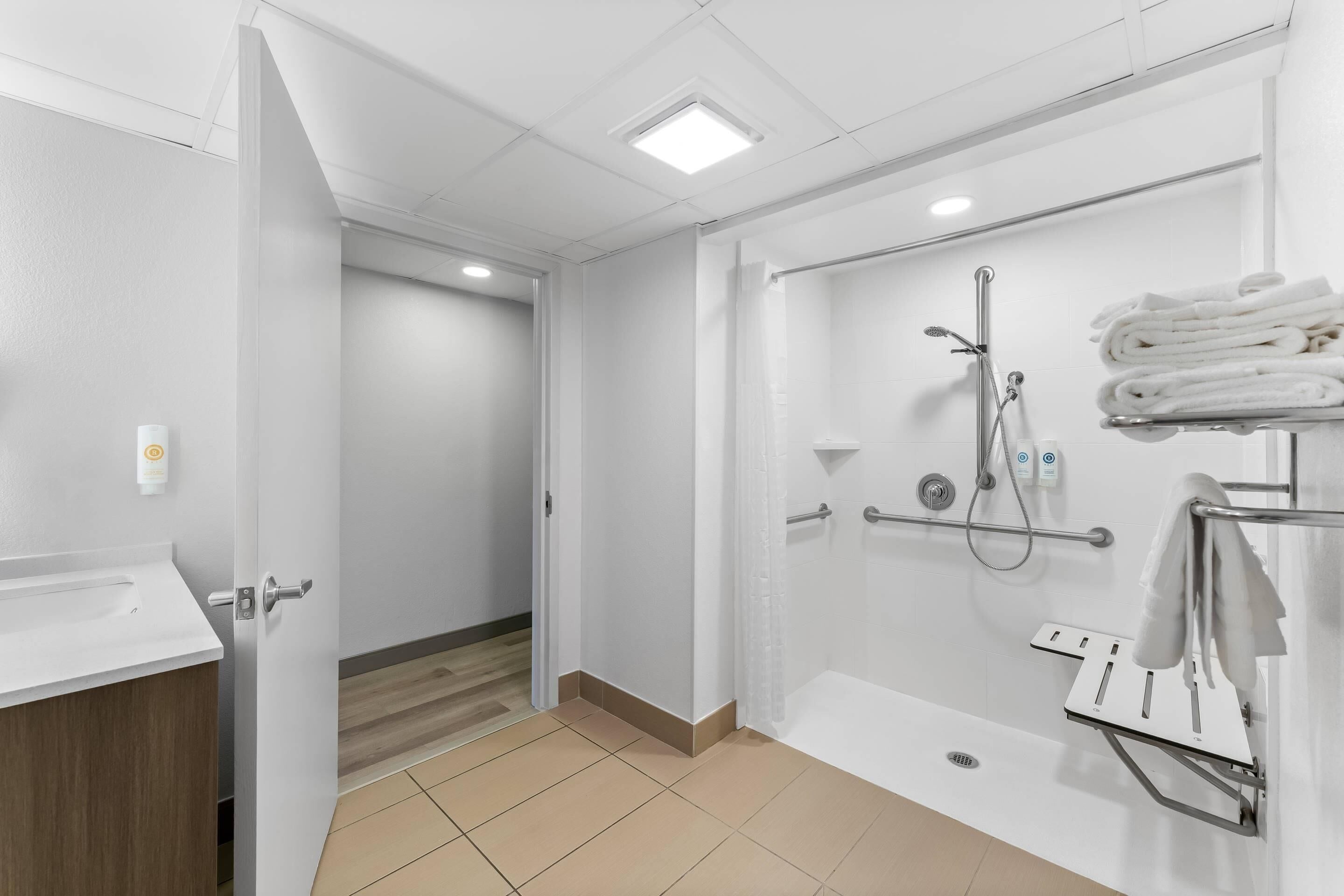 Un baño moderno con ducha, toallero y lavamanos.