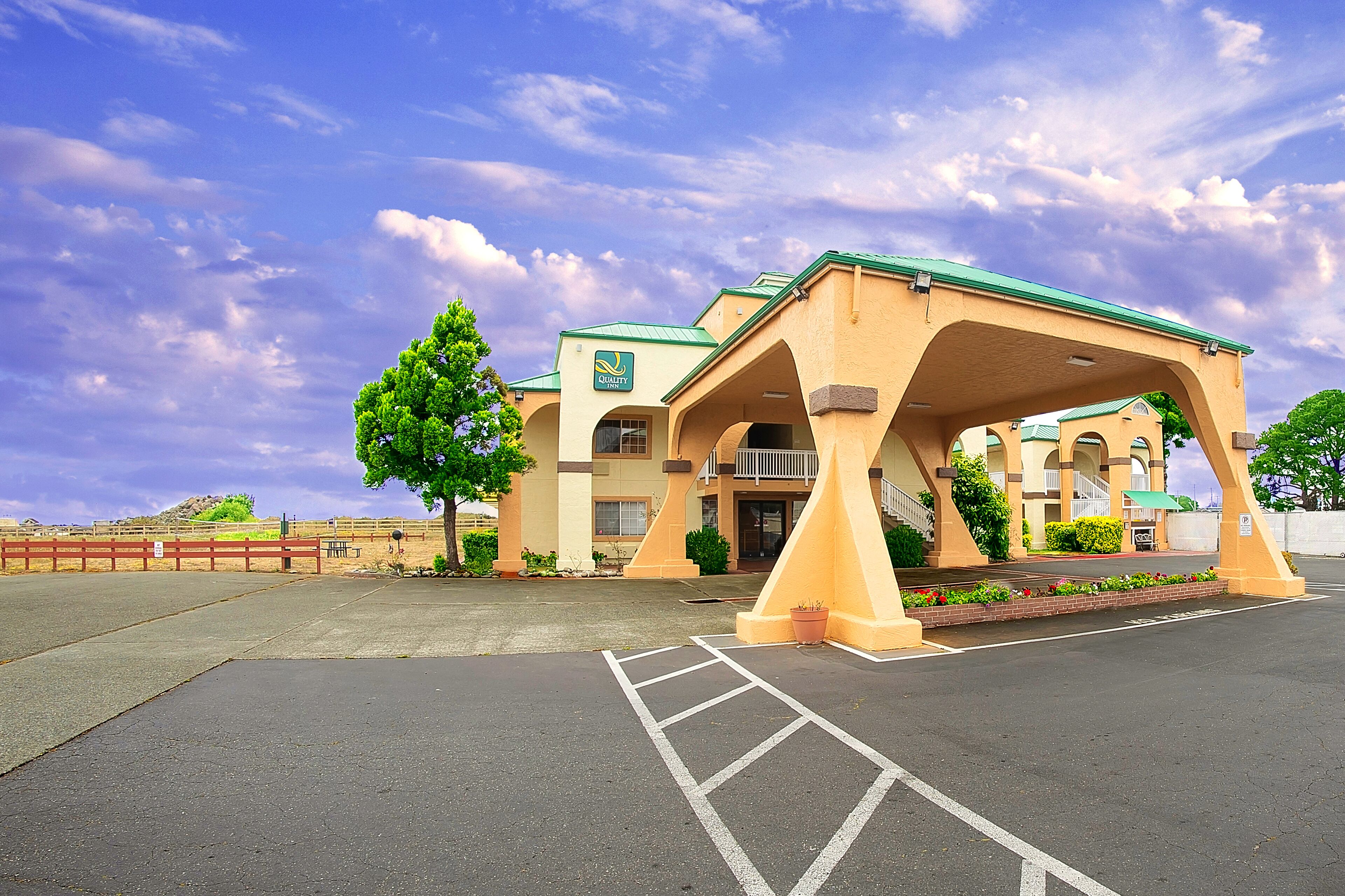 A hotel with a green roof, a covered entrance, and a parking lot.