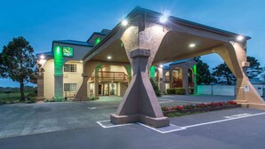 Un hôtel qui se distingue par son entrée en forme d’arche et son enseigne illuminée de couleur verte.
