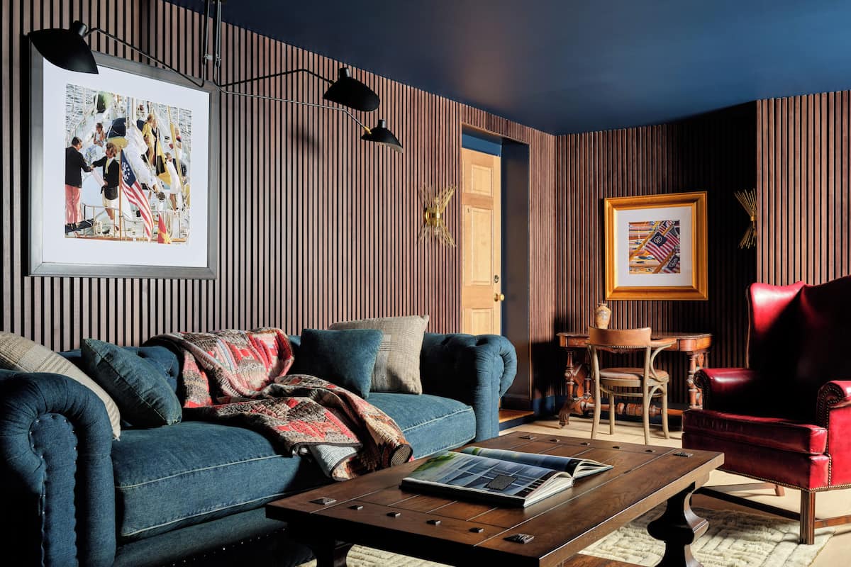 Una sala de estar moderna con un sofá azul, una mesa de centro de madera y un sillón rojo.