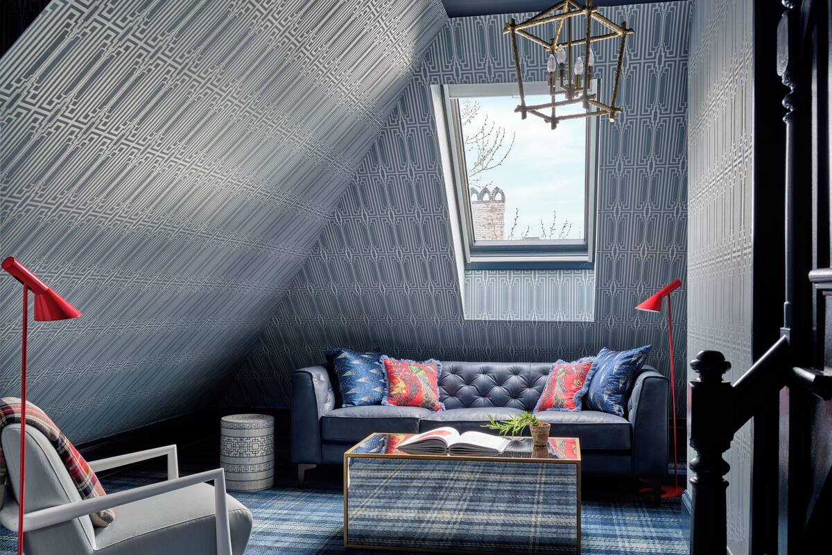 Un dormitorio tipo loft moderno con techo inclinado, un ventanal grande, un sofá, una silla y una mesita de centro.
