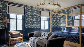 A bedroom with a four-poster bed, a sofa, a chair, and a large window.