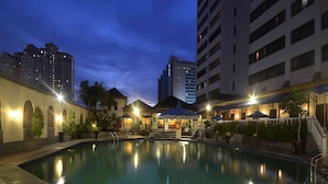 A swimming pool with a surrounding patio area, including a covered seating area and a small slide. - The Jayakarta Jakarta (Jakarta)