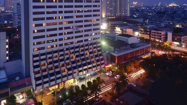 A high-rise hotel with multiple floors, a prominent sign at the top, and a busy street below with visible traffic. - The Jayakarta Jakarta (Jakarta)