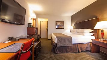 A hotel room with a bed, desk, chair, television, and a door leading to another room.