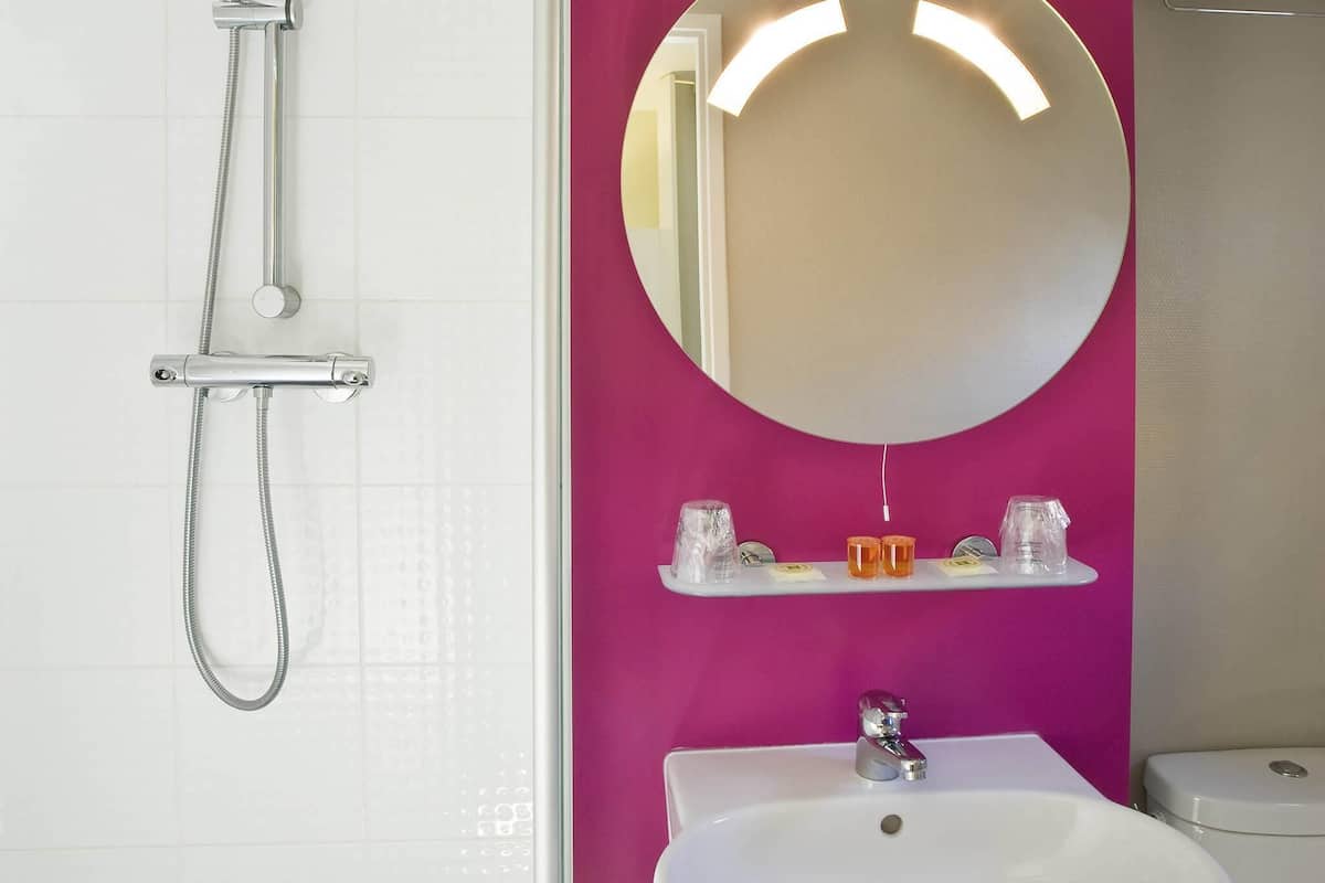 Une salle de bain avec un lavabo blanc, un miroir et une douche.