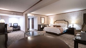 Una camera d'albergo con un letto, comodini, una scrivania, una sedia e un tavolino con piano in vetro.