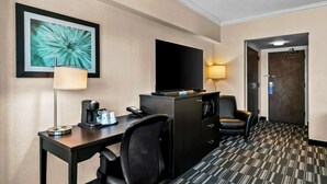 A hotel room with a desk, chair, television, and a bed.