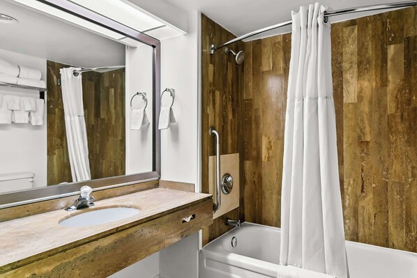 A bathroom with a wooden vanity, a sink, a mirror, a shower with a glass door, and a bathtub.