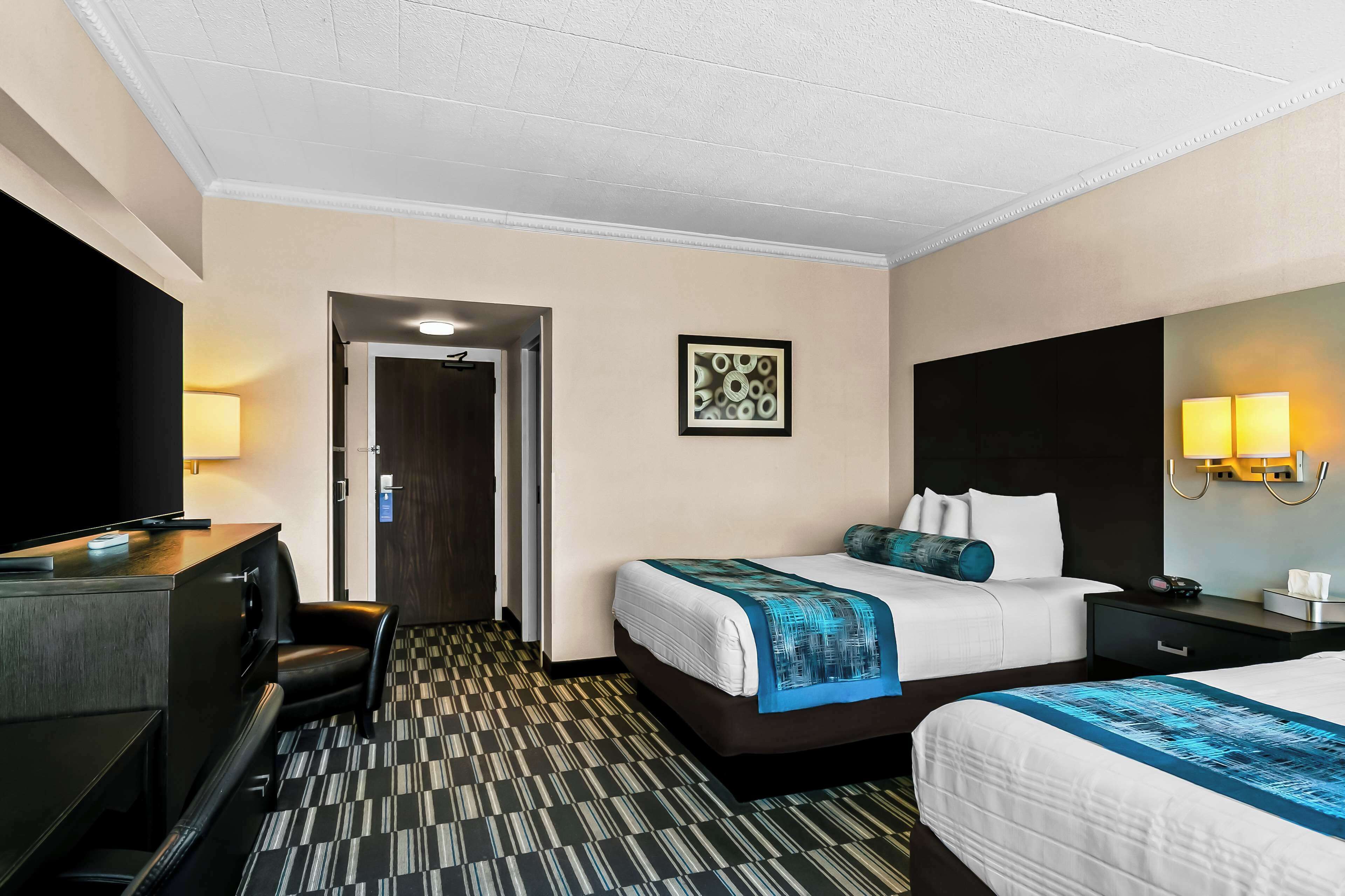 A hotel room with a bed, a desk, a chair, and a television.