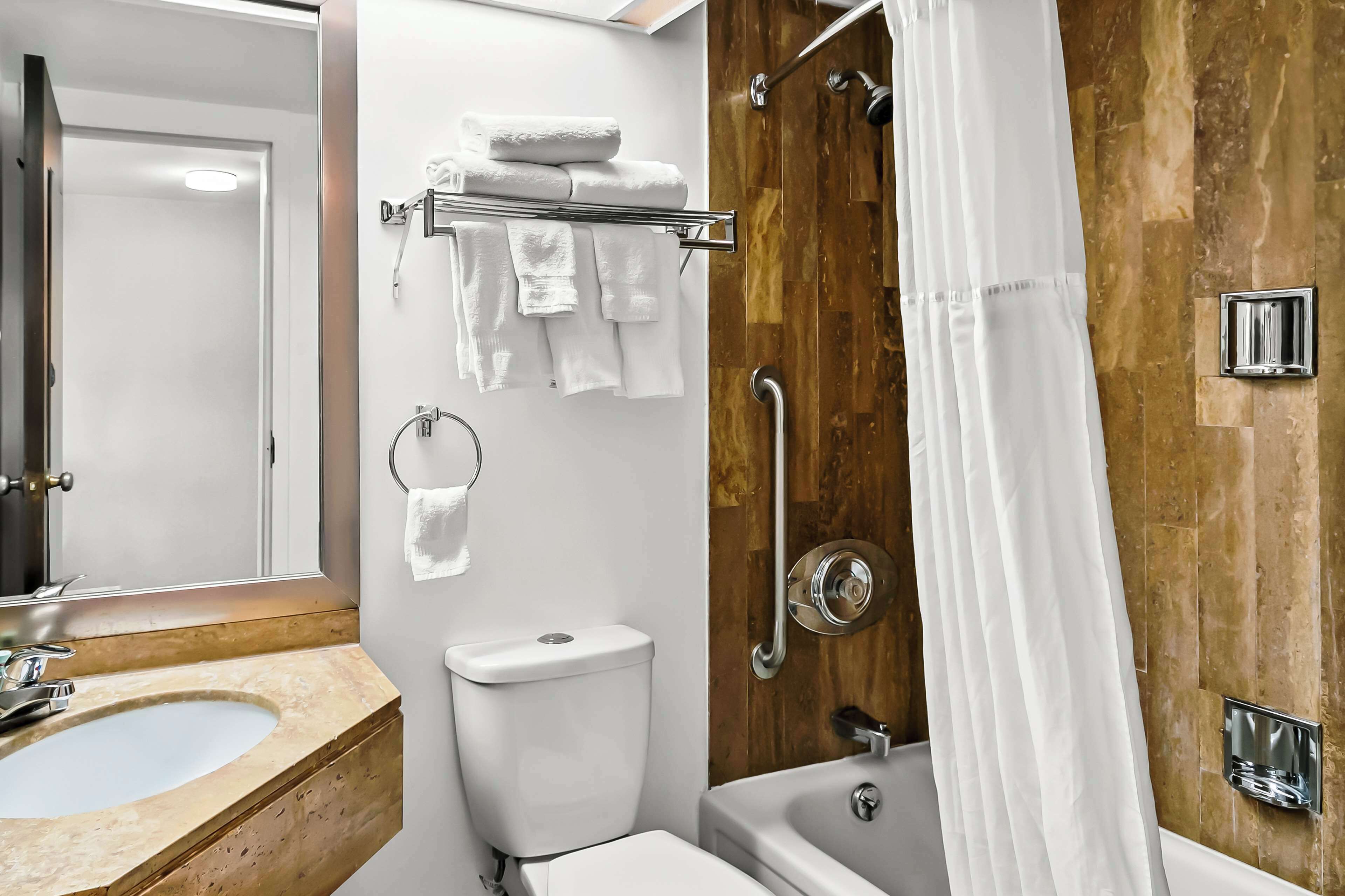 Un baño con pared de madera, inodoro blanco, lavabo y bañera.