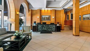 A lobby with a reception desk, seating area, and large windows.