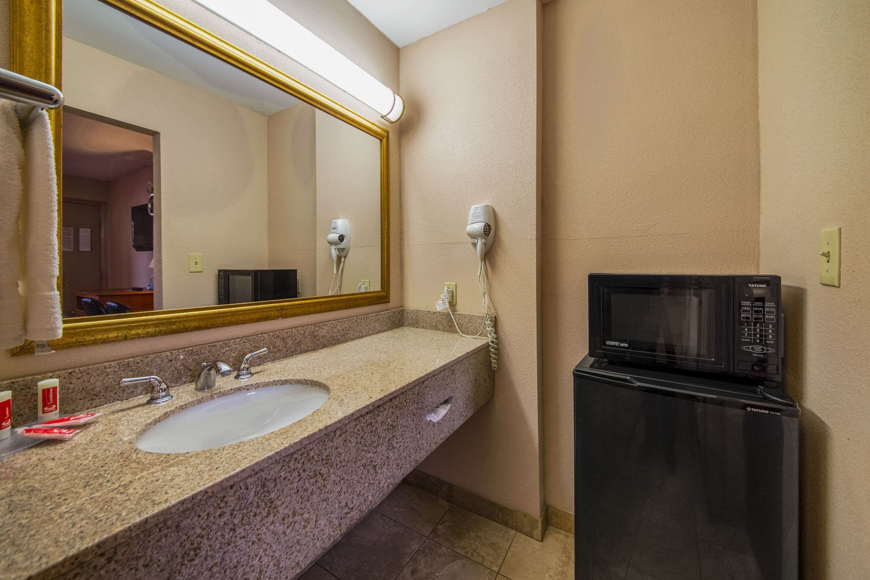 A bathroom with a sink, mirror, hair dryer, and a microwave.
