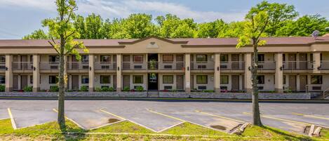 A motel with a central entrance, multiple balconies, and a parking lot.