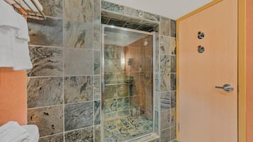 Ein Badezimmer mit Duschkabine, Marmorfliesen und Holztür.