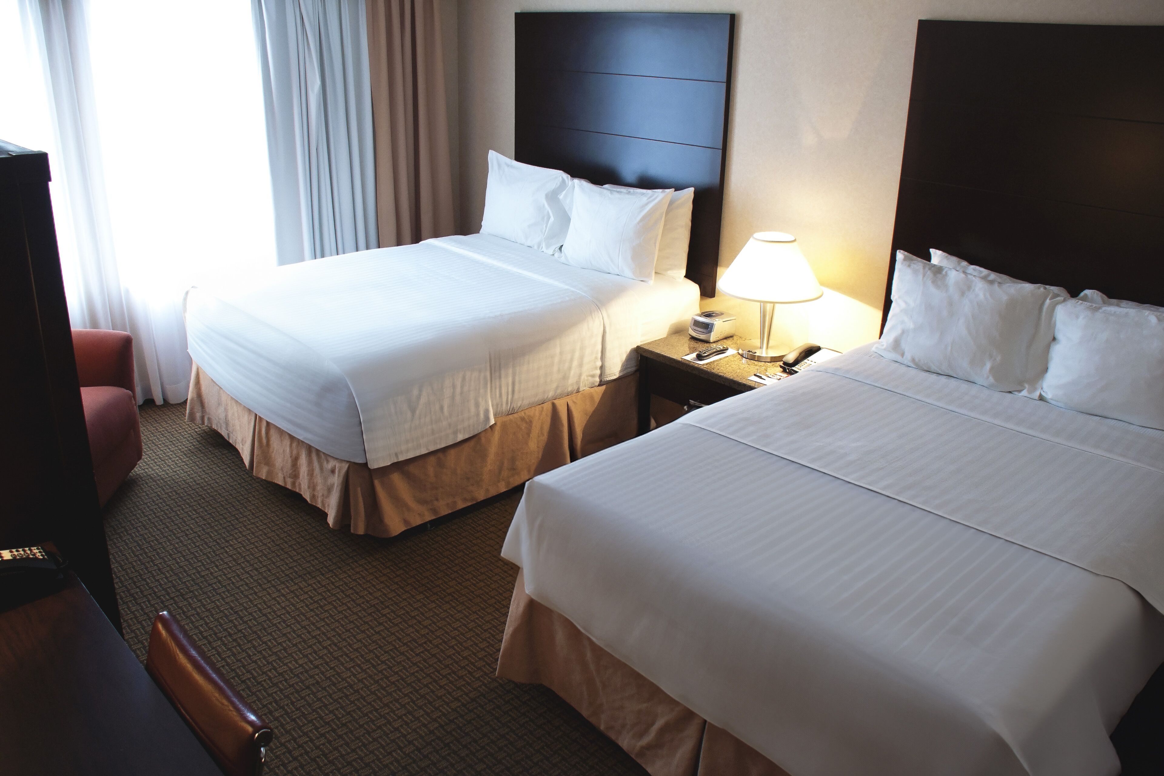 A hotel room with two beds, a desk, and a chair.