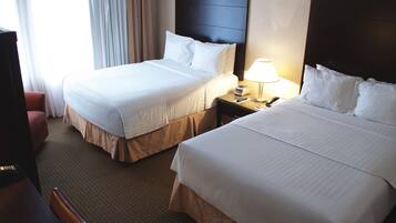 A hotel room with two beds, a desk, and a chair.