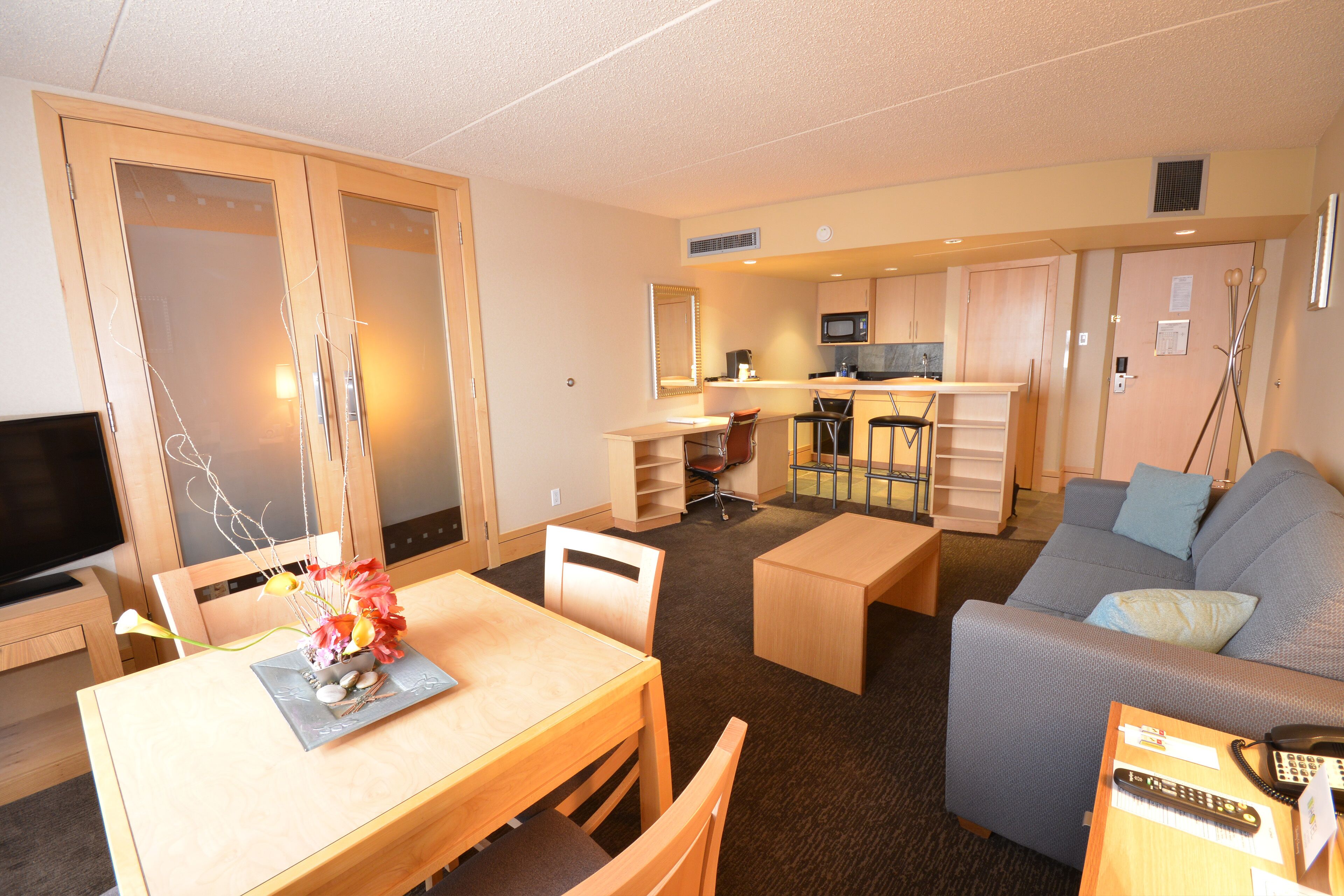 A compact hotel room with a dining area, kitchenette, and a sofa.