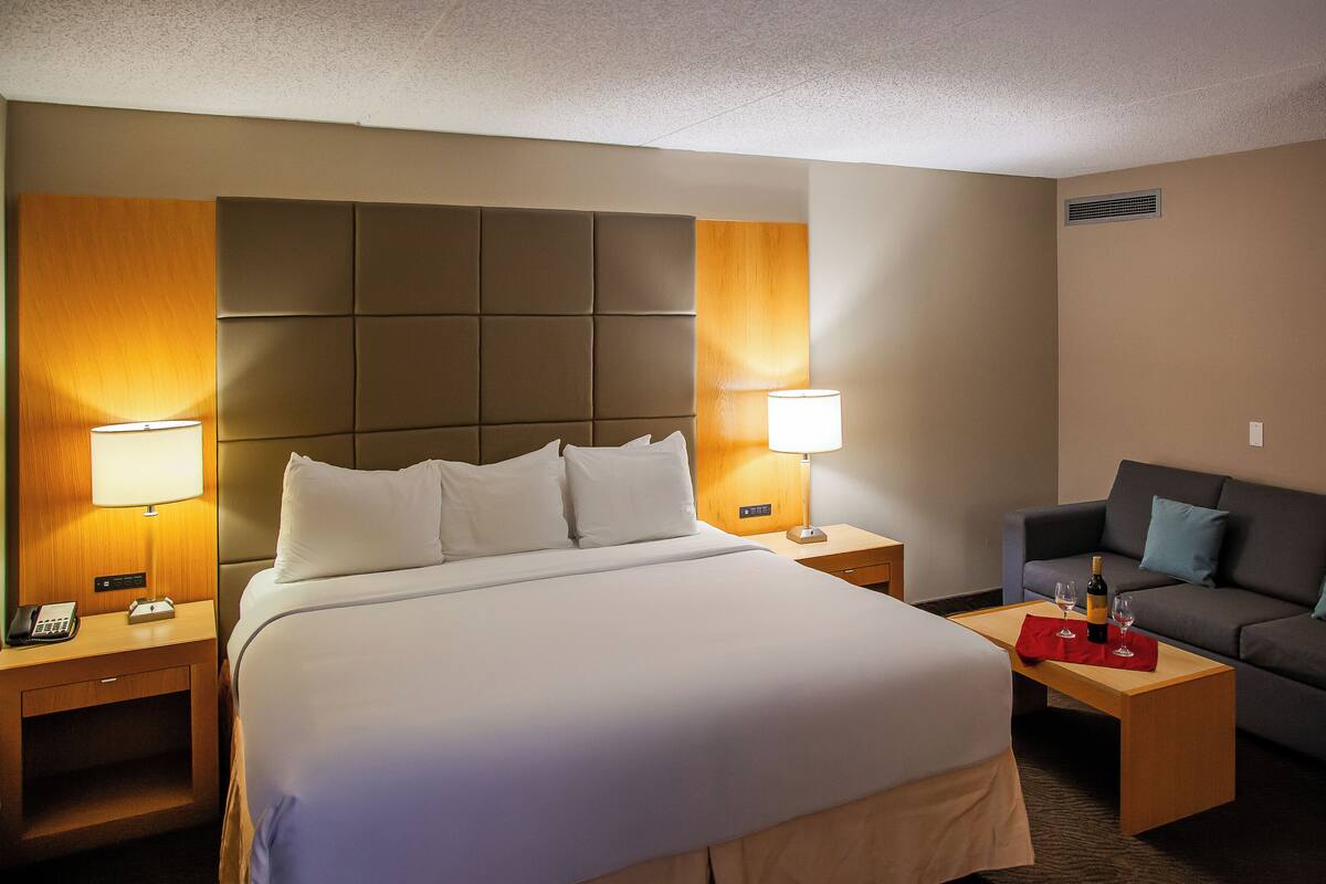 A hotel room with a large bed, two bedside tables, a sofa, and a nightstand.