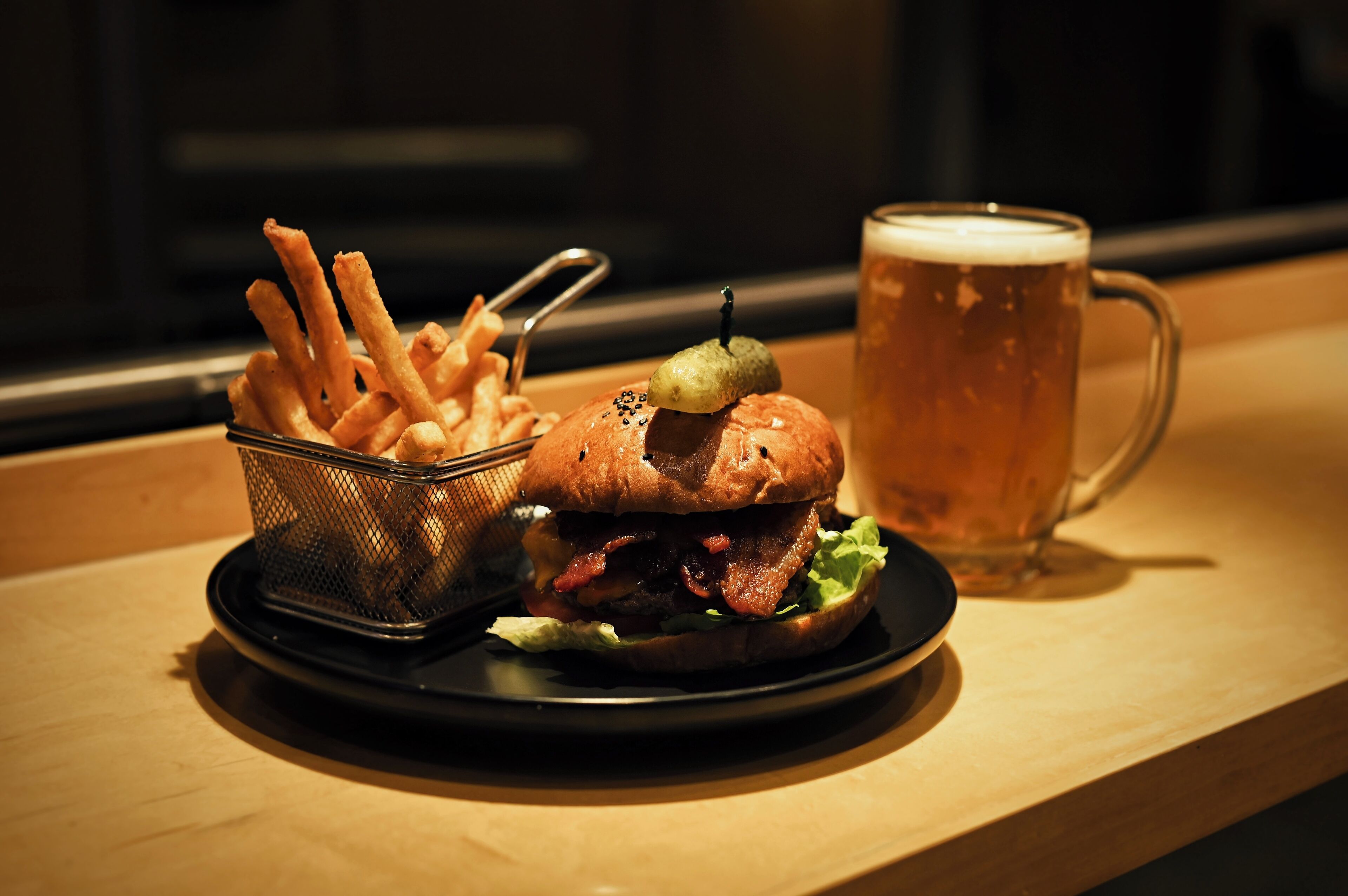 A burger with fries and a beer on a table.