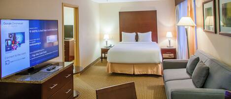 Una habitación de hotel con una cama, un televisor mostrando una aplicación del hotel, un escritorio con una lámpara y un sofá.