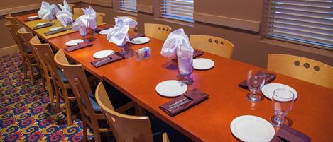 A dining area with a long table set for multiple guests, chairs, and a patterned carpet.