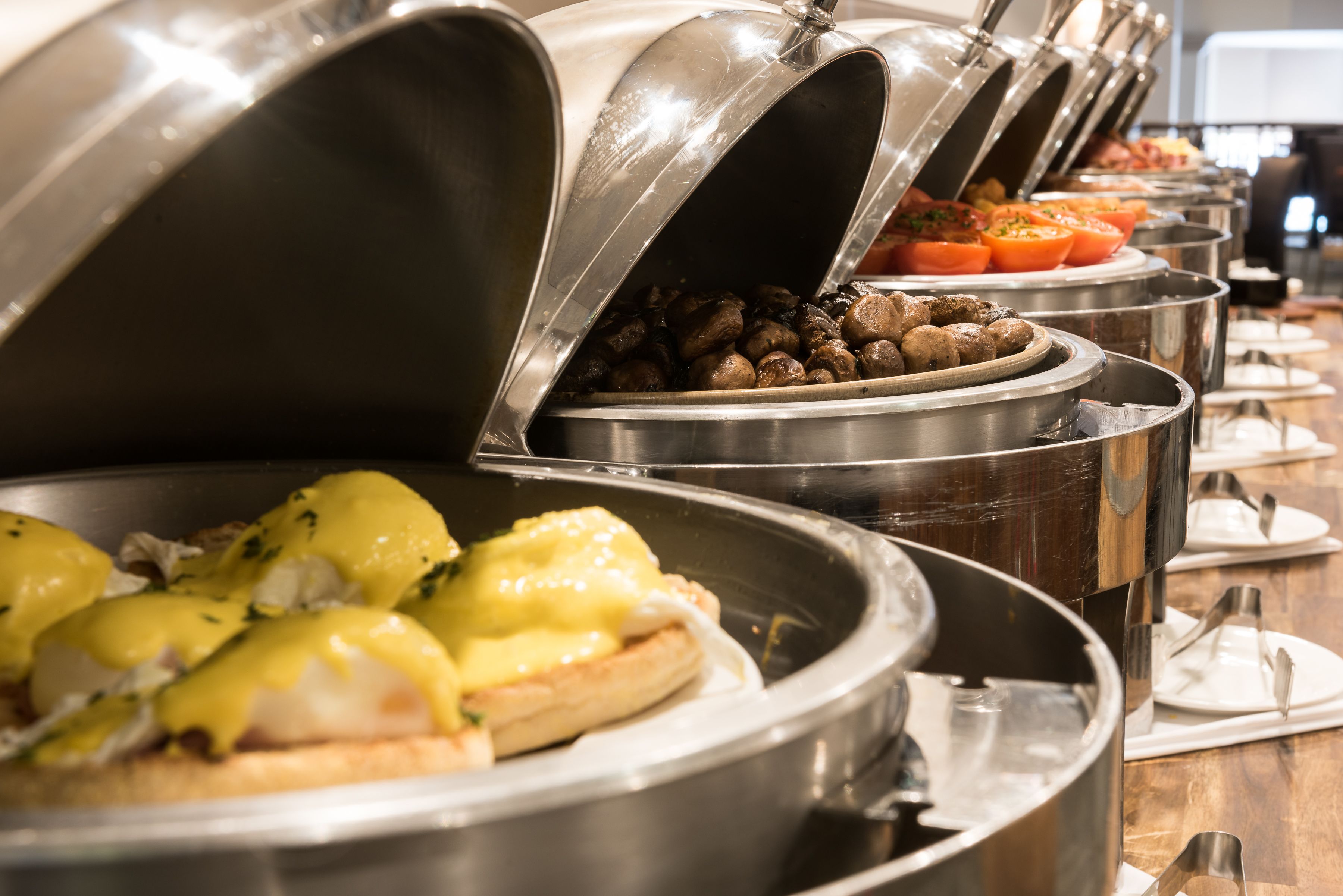 Een buffet met diverse gerechtjes, waaronder eieren Benedict en geroosterde aardappelen.
